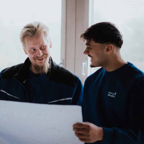 Zwei Elektrotechnik Kollegen schauen auf einen großen Bauplan
