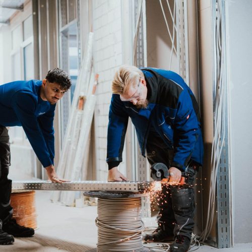 Elektroniker schneidet Metall mit einer Flex, Funken sprühen